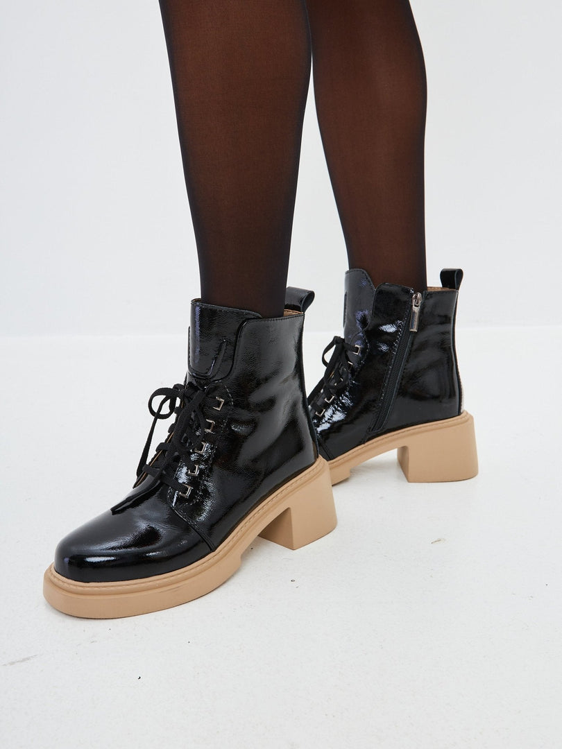 A pair of stylish patent leather lace-up ankle boots in black, perfect for women seeking trendy patent leather footwear.