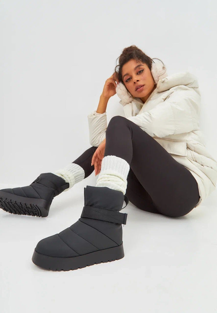 A pair of stylish black winter boots with cozy wool lining, perfect for cold urban days.