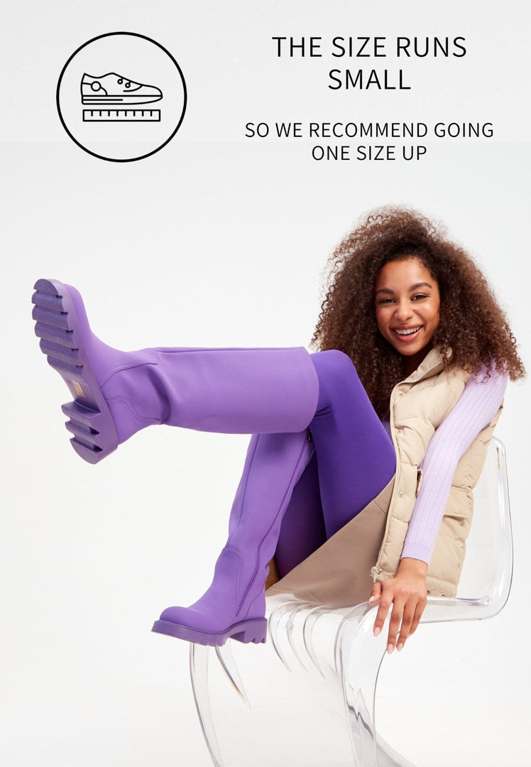 A stylish pair of women's fashion boots in a bold purple color, featuring knee-high design and chunky soles.