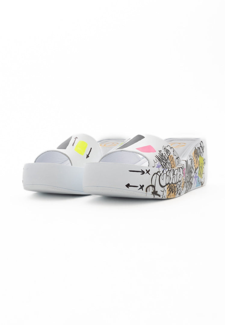 A close-up of stylish white platform mule shoes on a wooden floor, perfect for a chic and trendy look.
