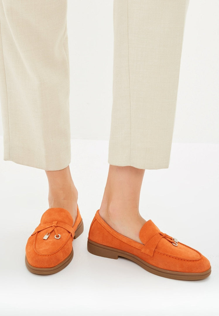 A pair of stylish men's classic loafers in orange with a flat sole, perfect for fashion-forward footwear.