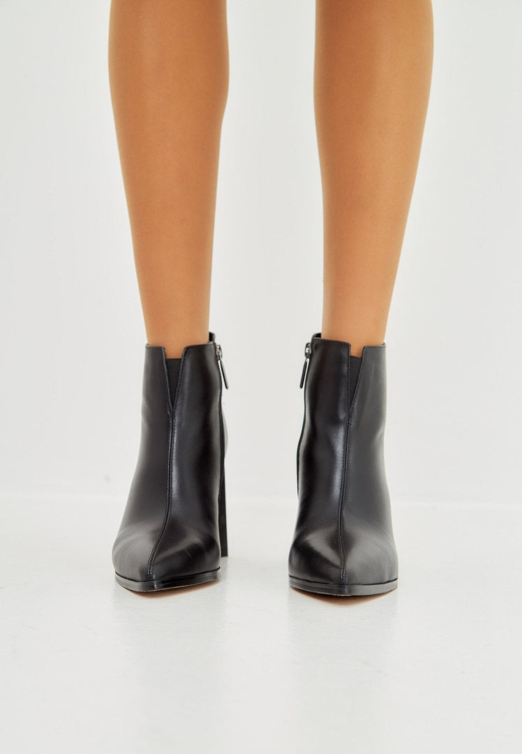 A trendy pair of black pointed toe ankle boots with block heels, made of stylish leather.