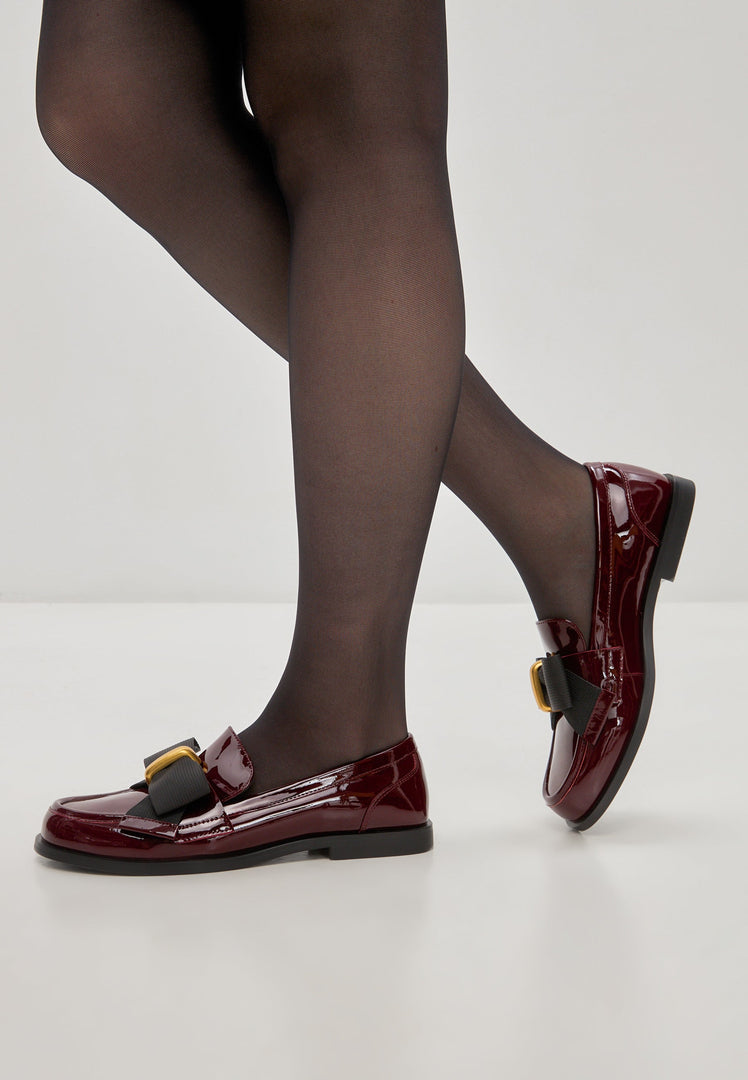 A stylish pair of women's dress shoes, featuring elegant black bow loafers and eye-catching patent red Dorothy loafers.