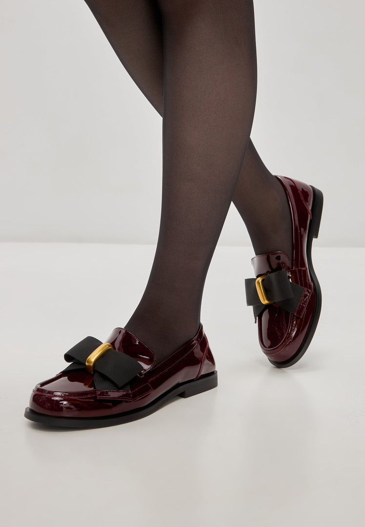 A stylish pair of women's dress shoes, featuring elegant black bow loafers and eye-catching patent red Dorothy loafers.