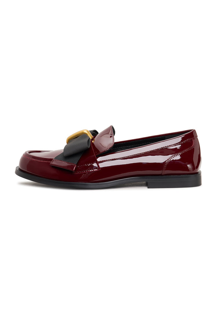 A stylish pair of black bow loafers, also known as Dorothy loafers, featuring an elegant design perfect for women's dress shoes, along with patent red accents.