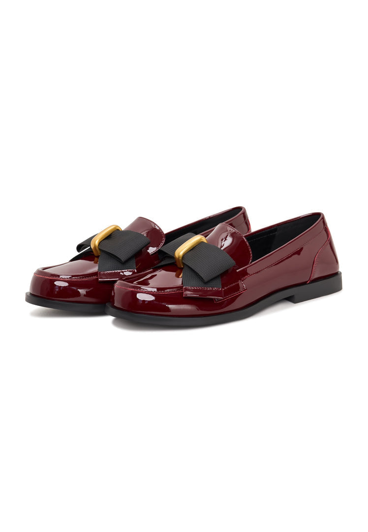 A chic pair of women's dress shoes with a timeless design featuring elegant black bow loafers, also known as Dorothy loafers, in a shiny patent red finish.