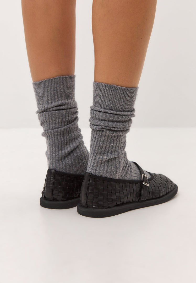A pair of elegant black Mary Janes with woven details for stylish women's fashion.