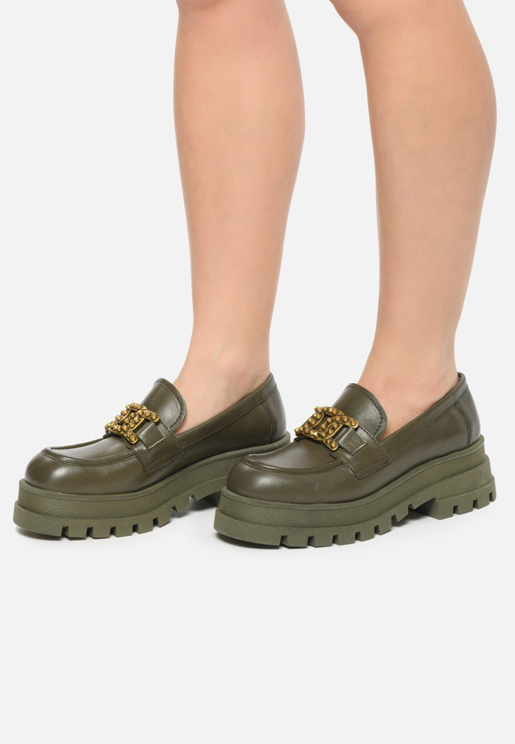 A pair of dark green studded loafers, stylish and chunky women's fashion footwear.