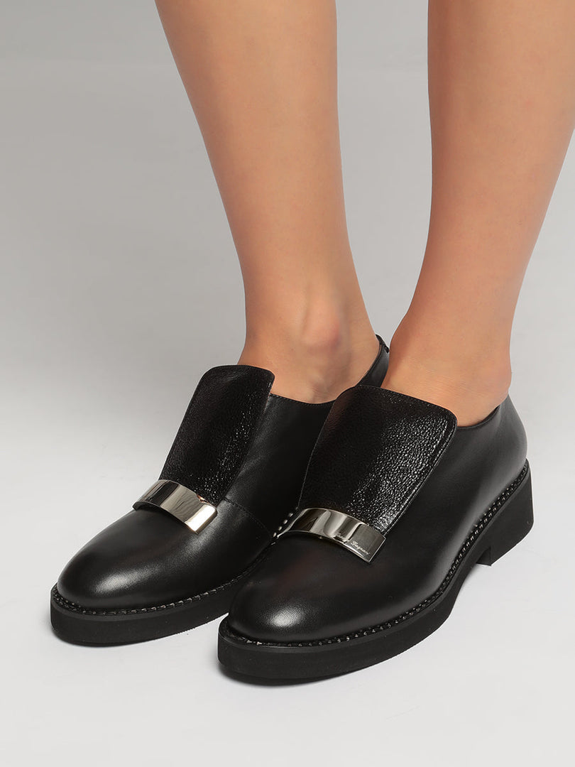 A pair of men's leather slip-on loafers with a stylish metal accent design, the perfect fashionable choice for any outfit.