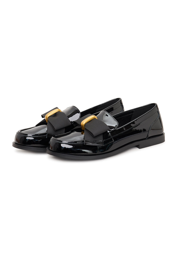 A pair of elegant patent black women's loafers with a stylish gold bow, reminiscent of Dorothy's iconic footwear.