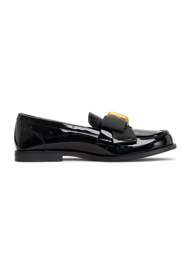 A pair of women's elegant patent black loafers with a gold bow detail, reminiscent of Dorothy's iconic shoes.