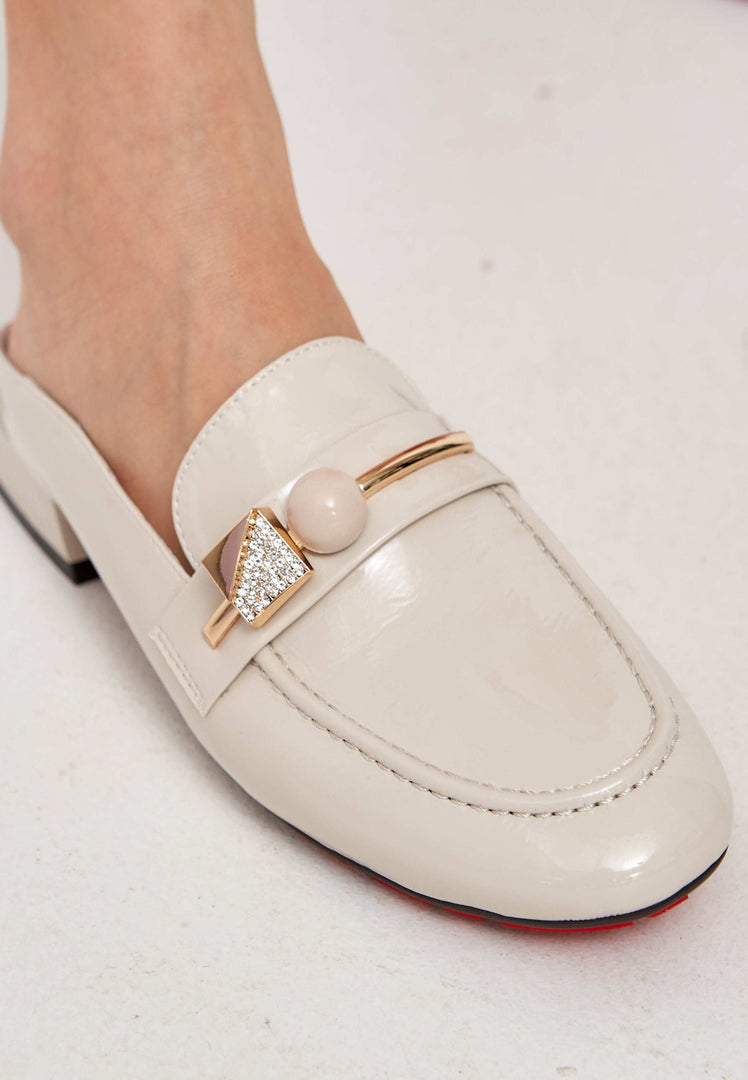 A stylish pair of women's white mule shoes with a glossy charm design, perfect for those seeking elegant and trendy footwear.