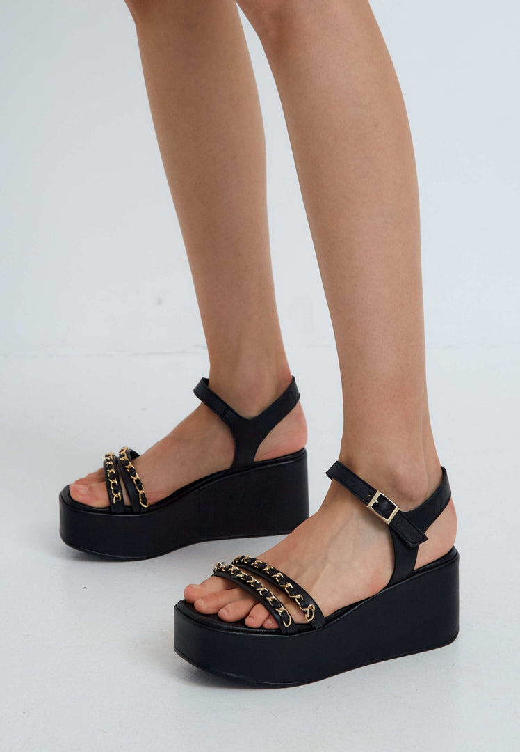 A chic pair of black platform sandals with gold chain accents, perfect for all women's fashion-forward footwear looks.