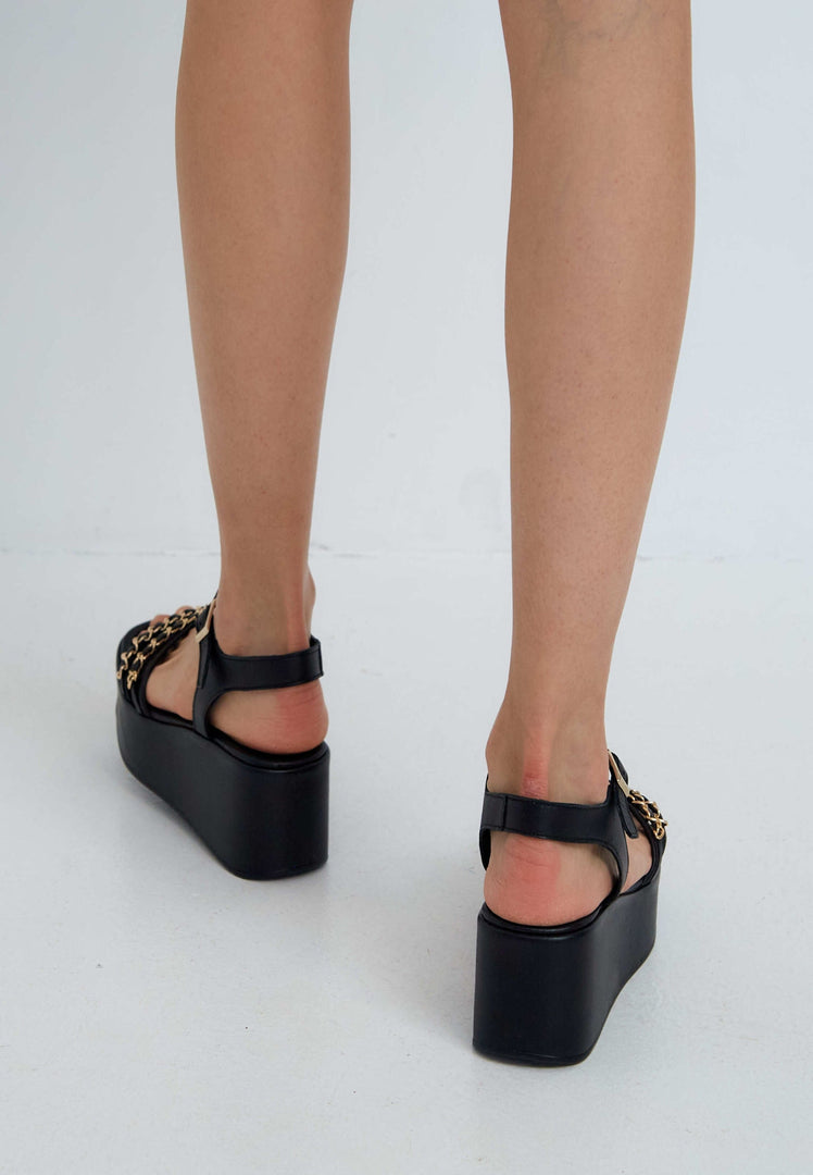 A stylish pair of black platform sandals for women featuring trendy gold chain accents, perfect for any fashionable shoe lover.