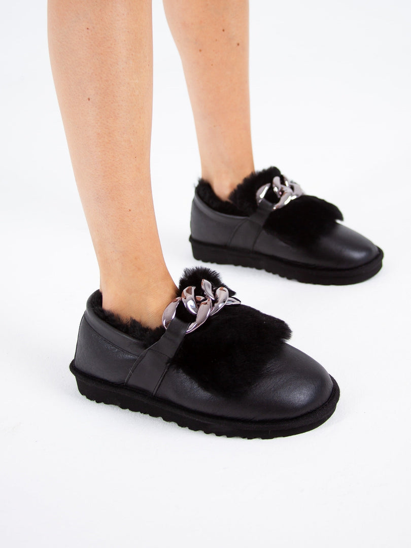 A pair of stylish black fur lined loafers with chain detail, ideal as women's winter shoes for a chic and casual look.