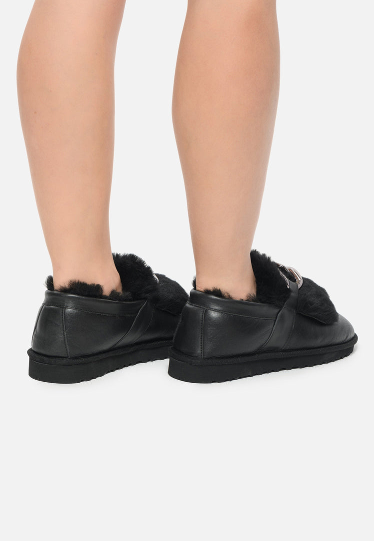 A close-up image of black fur lined loafers with chain detail, perfect for women's winter shoes for a stylish and casual look.