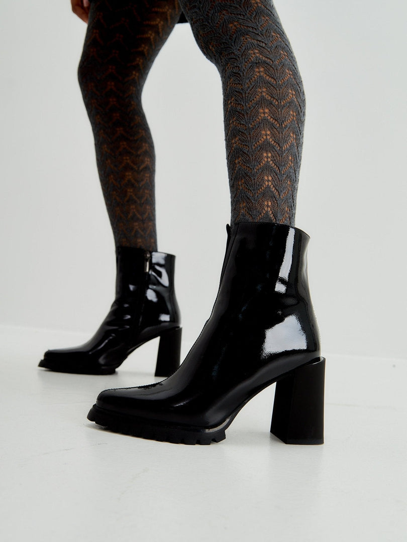 A stylish pair of black patent leather ankle boots, a classic choice in women's footwear.