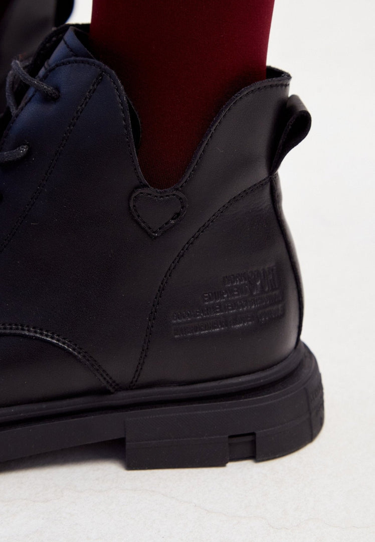 A stylish pair of women's black leather flat sole ankle boots with a flat heel design.