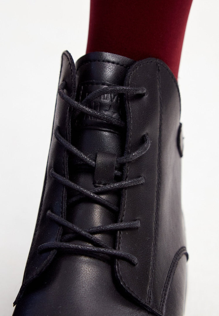 A stylish pair of black leather flat sole ankle boots for women, featuring a sleek design with a flat heel.