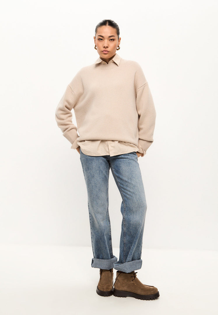 A classic crew neck Mulan sweater in beige for women, featuring a cozy knit pullover design.