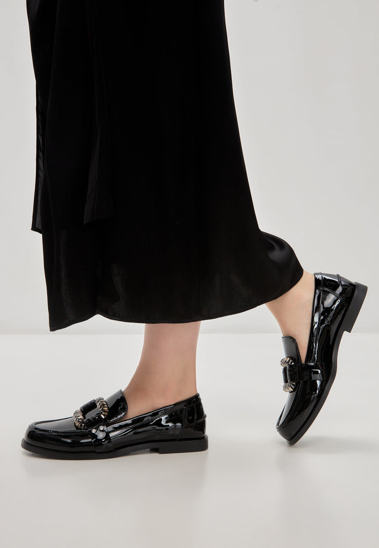 A pair of elegant black patent loafers adorned with sparkling crystals, known as Bagheera loafers, perfect for adding a touch of glamour to any outfit.
