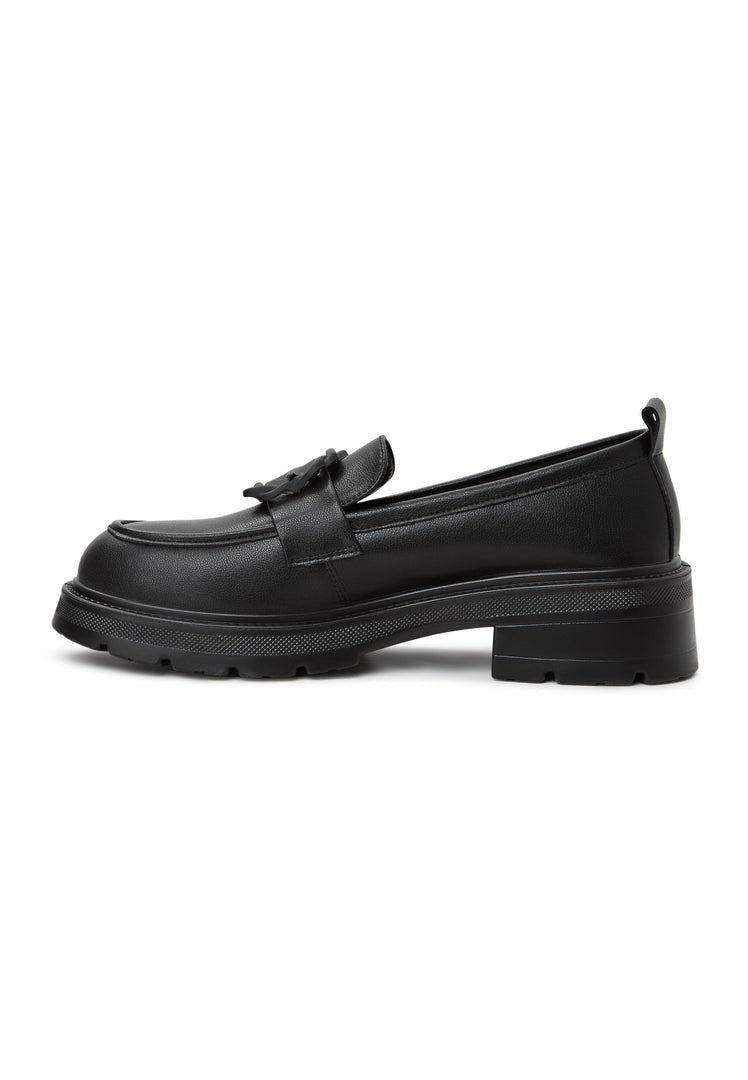 A woman wearing black platform loafers with a traditional sari, showcasing a stylish fusion of women's footwear fashion.