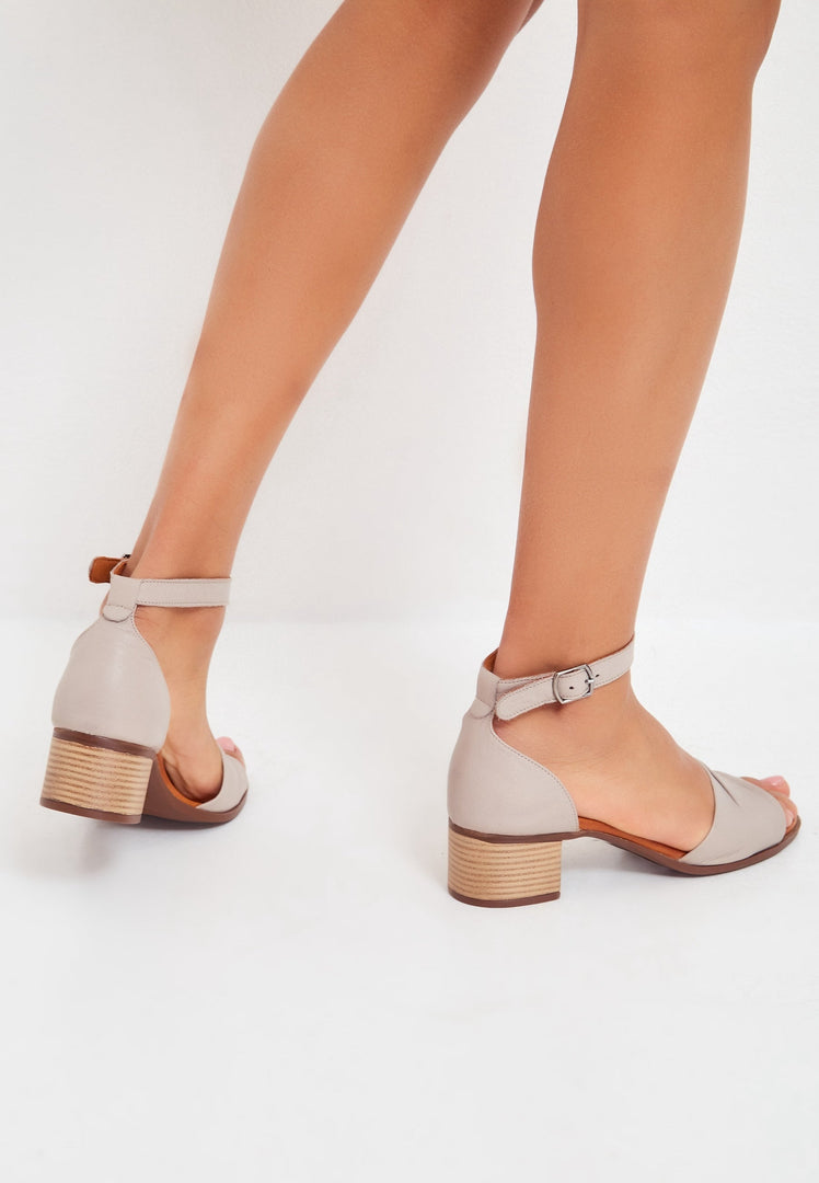 A pair of stylish beige block heeled sandals for women, perfect for adding a fashionable touch to any outfit.