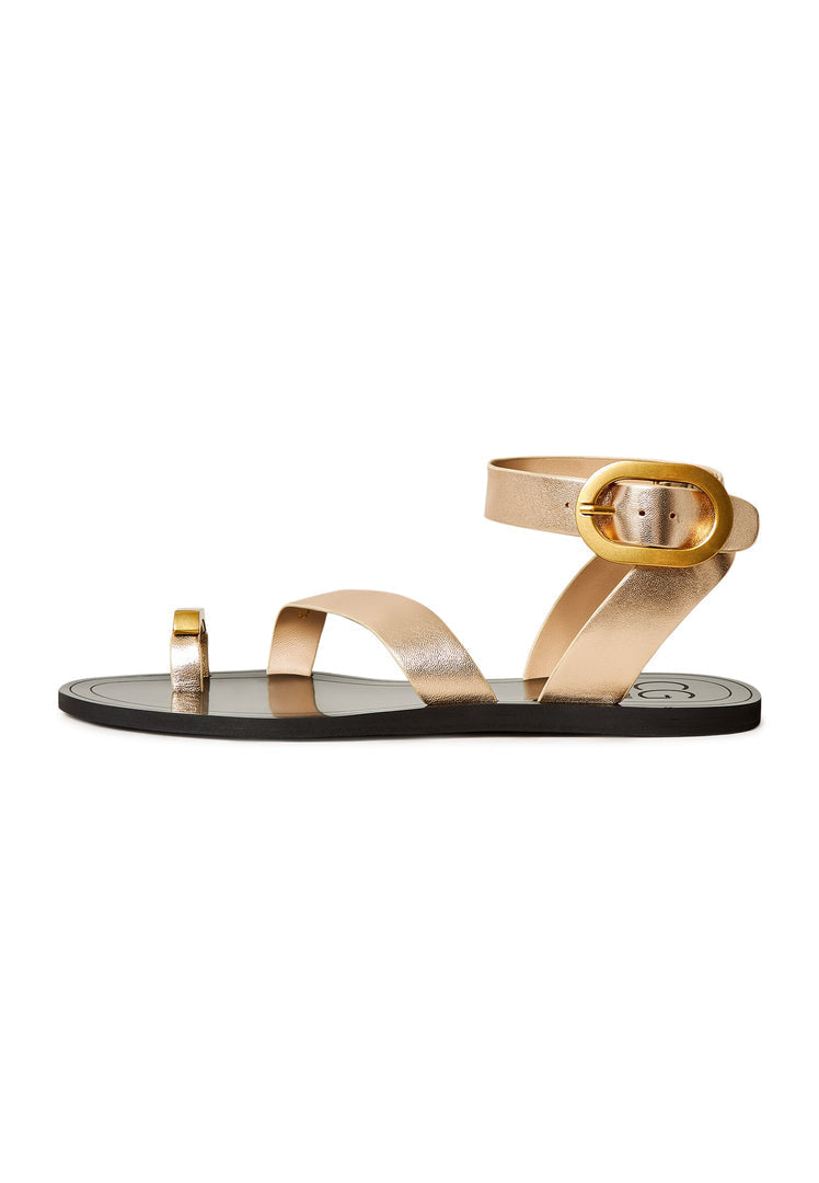 A pair of chic gold Paula flat sole sandals for women, perfect for casual wear.