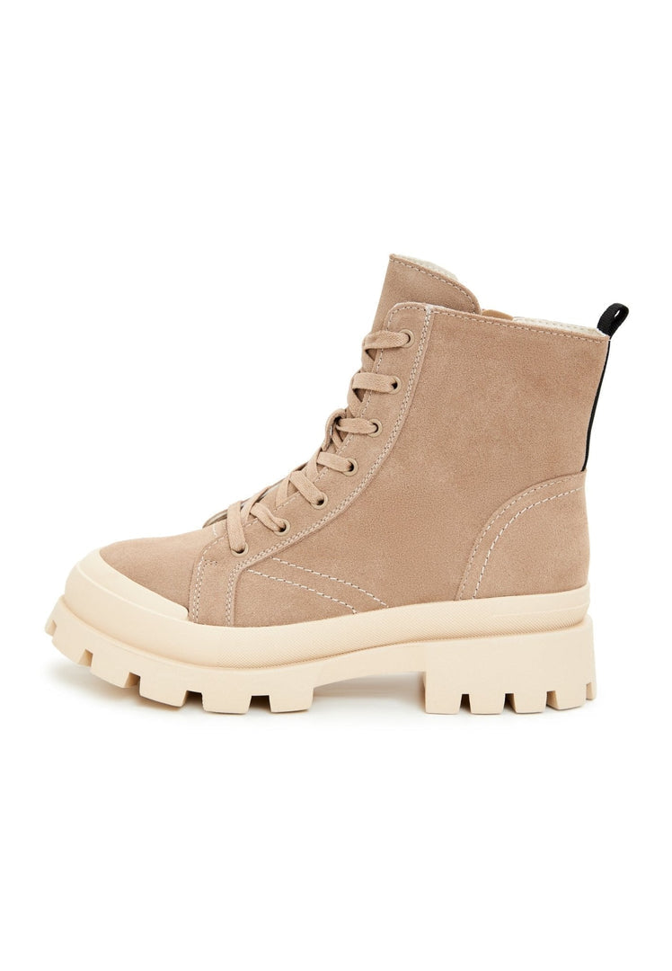A fashionable woman wearing trendy ankle booties, urban lace-up ankle boots, and chic lace-up boots, showcasing stylish urban footwear for a fashionable street style look.