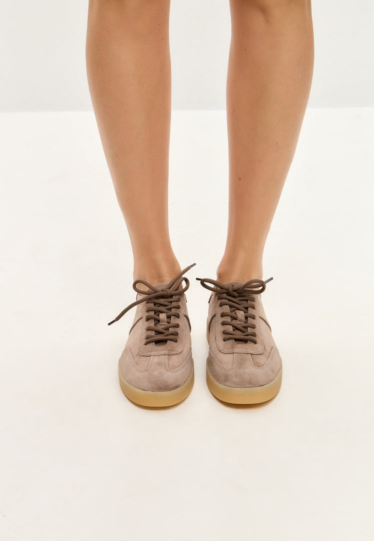 A stylish pair of low-top classic suede sneakers in beige, perfect for on-trend footwear fashion.