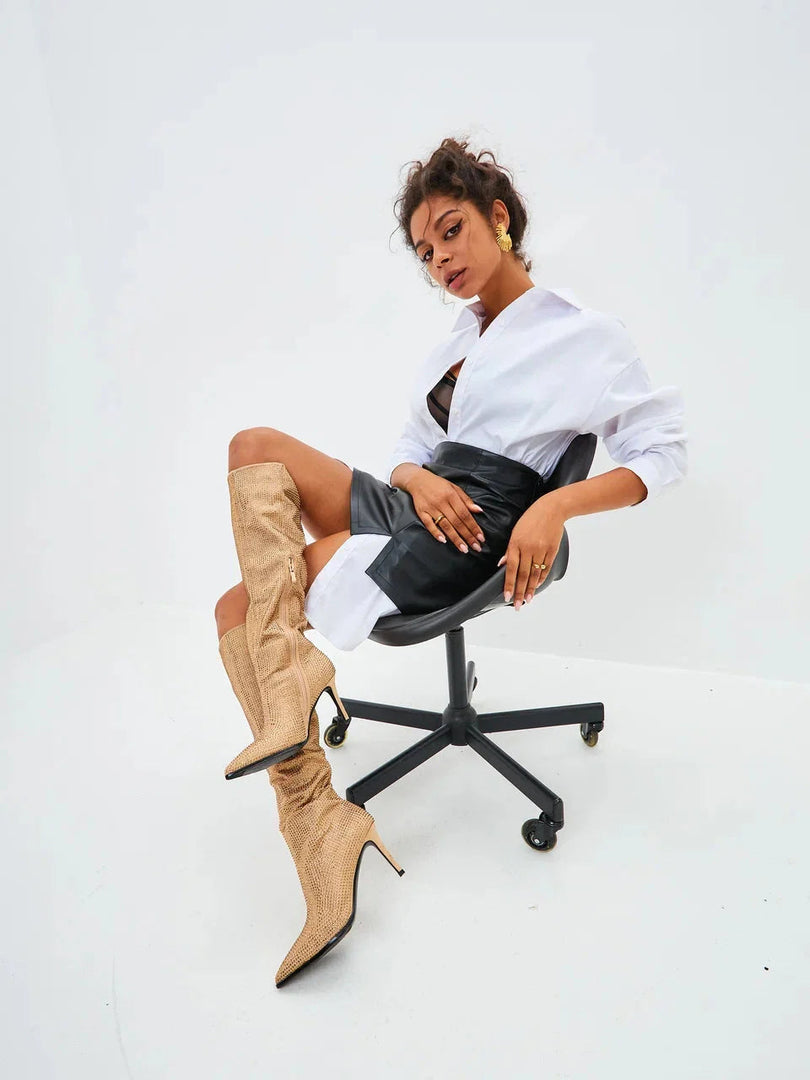 A fashionable pair of knee-high gold stiletto boots with jewel embellishments, also known as Mili stiletto boots.