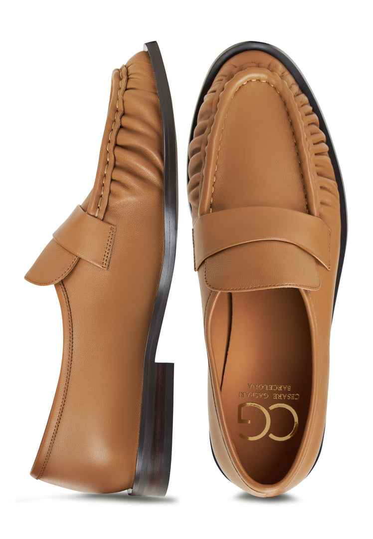 A woman wearing classic beige leather loafers by Isabel, a stylish choice in women's shoes.