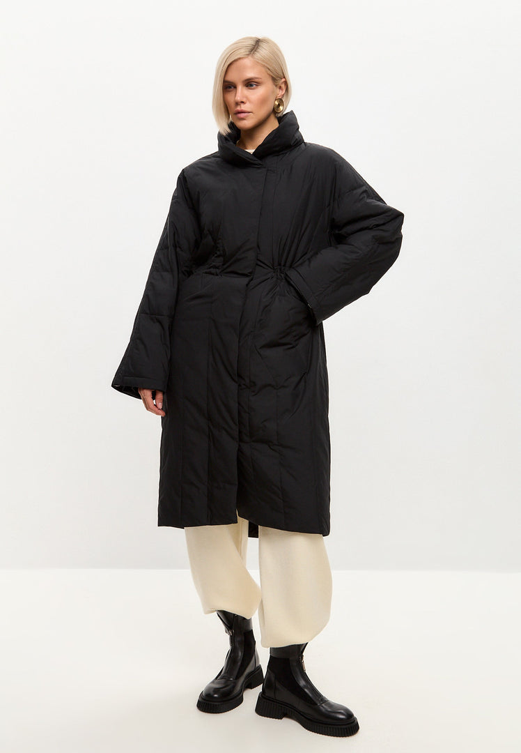 A stylish black quilted coat with a long silhouette for women's winter outerwear, providing both warmth and fashion-forward style.