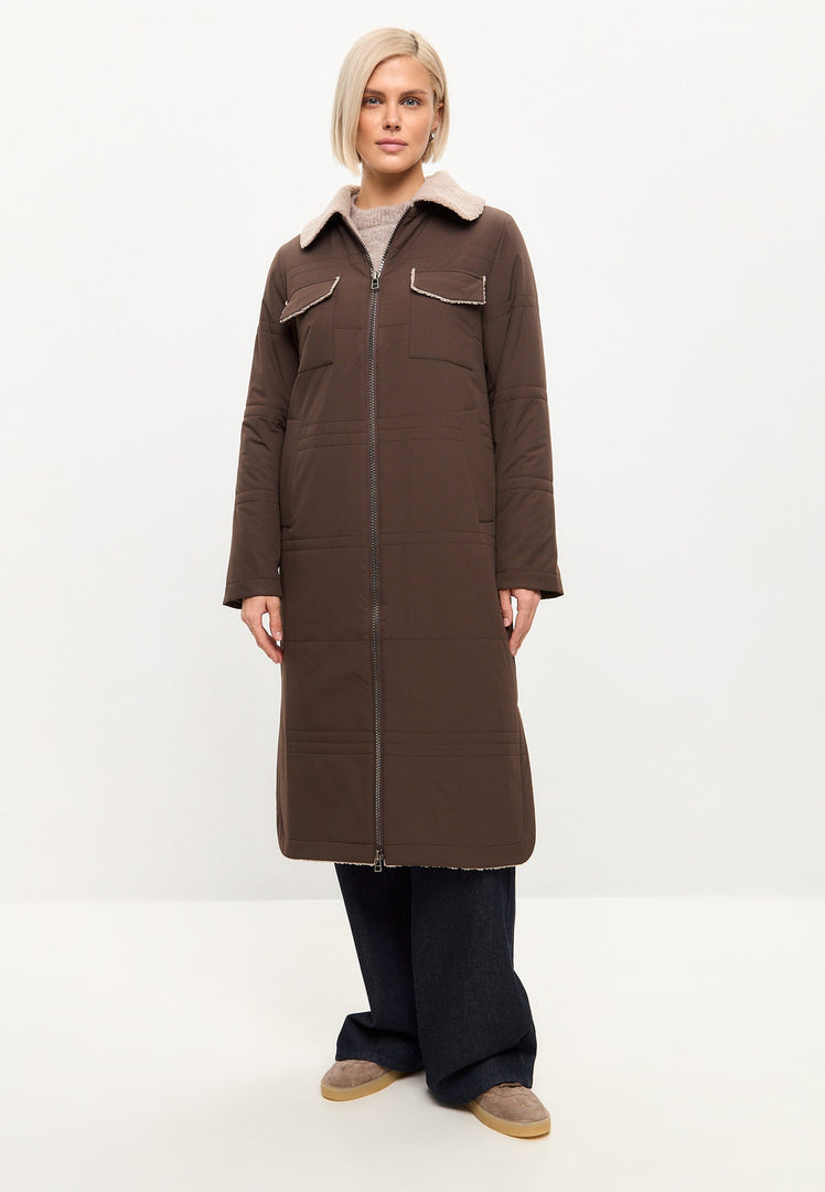 A fashionable woman wearing a trendy long coat with shearling collar and belt, perfect for winter styling.