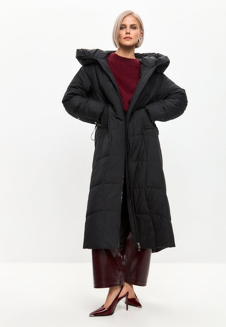 A stylish woman wearing an oversized hooded puffer coat, a plus size winter parka, and a long puffer coat to keep warm and stylish during winter.