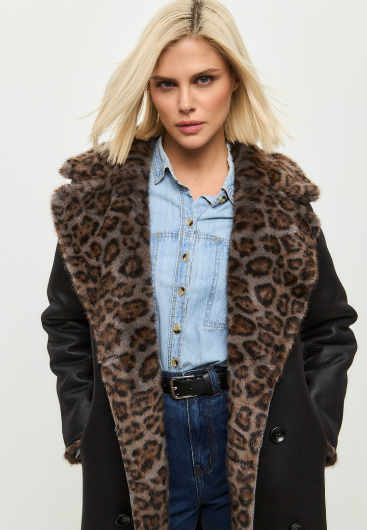 A stylish woman wearing a trendy faux shearling and animal print reversible long coat, perfect for the winter season.