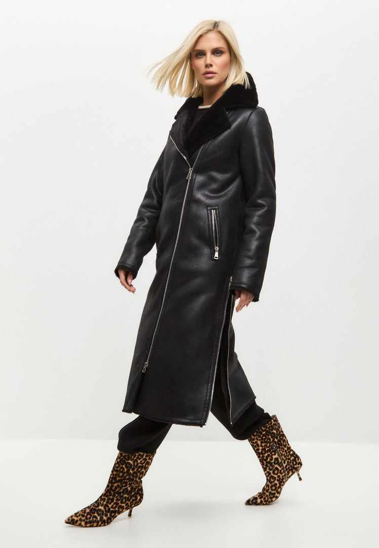 A stylish woman wearing a trendy black shearling coat, featuring a reversible design, perfect for staying warm and fashionable in women's winter outerwear.