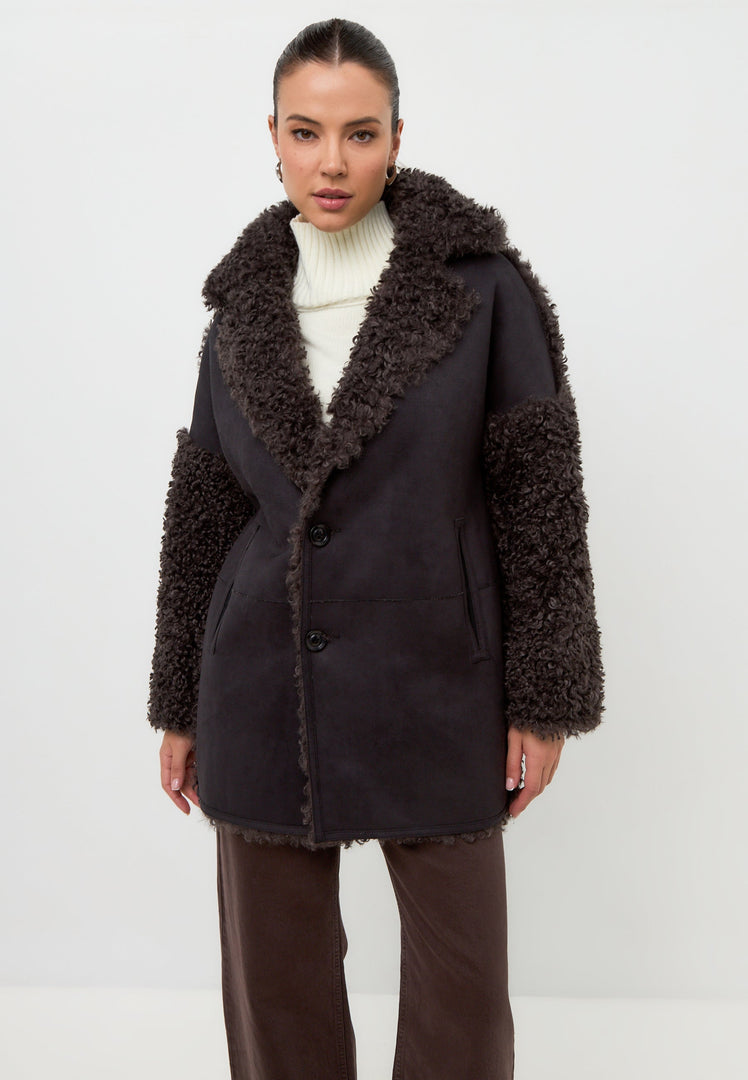 A woman wearing a cozy brown shearling Eva coat, a stylish and warm choice for winter.