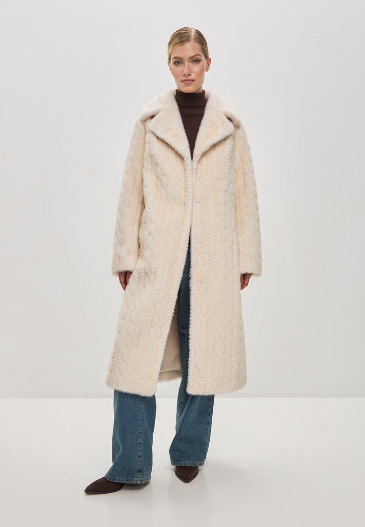 A woman wearing an elegant cream cable knit coat with faux fur trim, a stylish and cozy choice for the winter season.