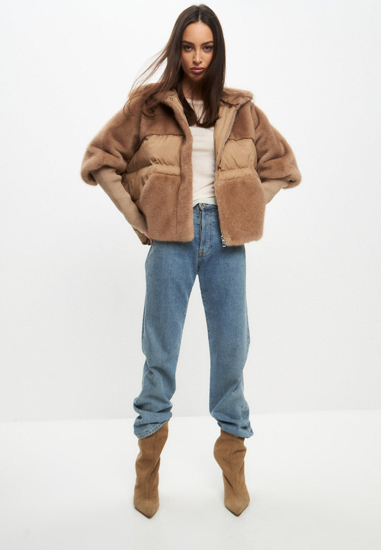 A stylish woman wearing an oversized beige faux fur jacket, perfect for winter outerwear and adding a touch of fashion to any outfit.