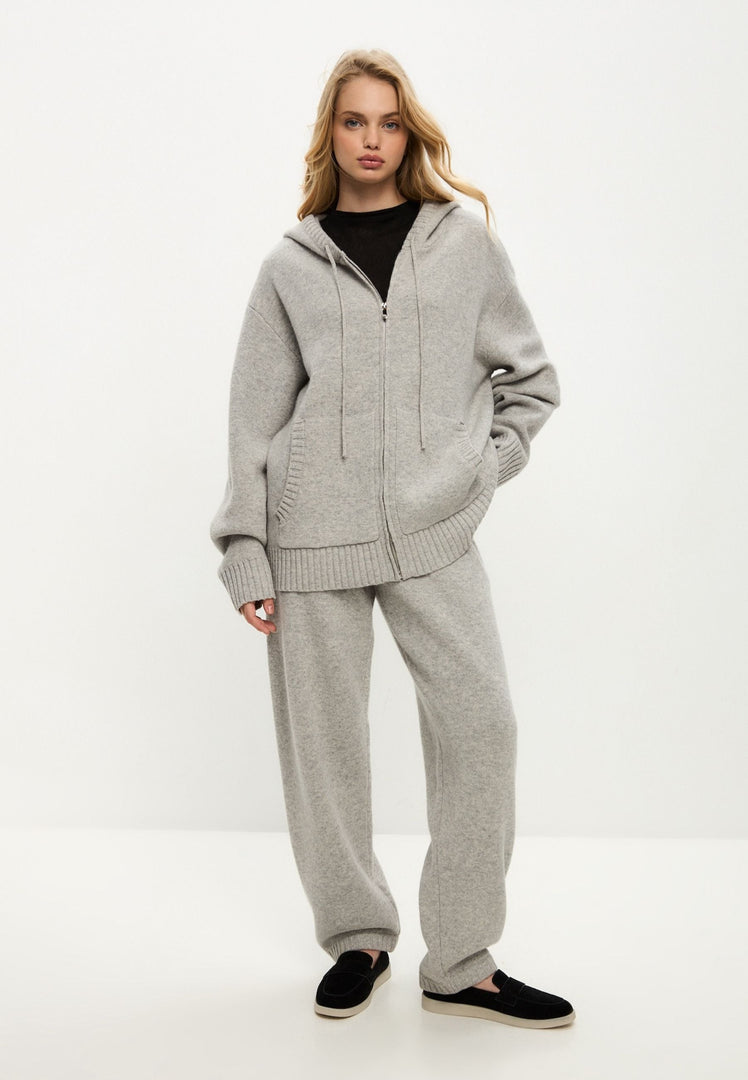 A woman wearing a stylish Penelope grey cardigan, a Merino hooded cardigan costume with intricate knitwear fashion details, perfect for layering in chilly weather.
