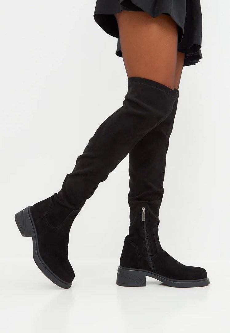 A fashion-forward woman wearing stylish and chic suede over-the-knee boots, showcasing trendy women's footwear.