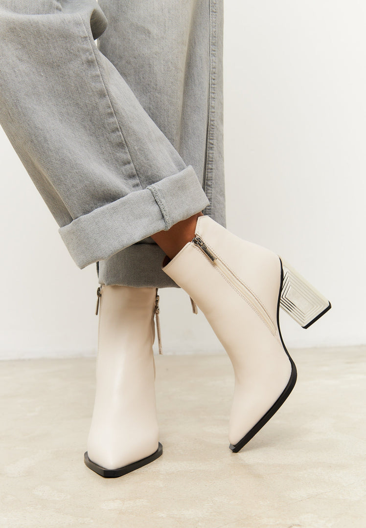 A stylish pair of women's leather ankle boots in classic beige, perfect for fashion-forward individuals looking for designer footwear.