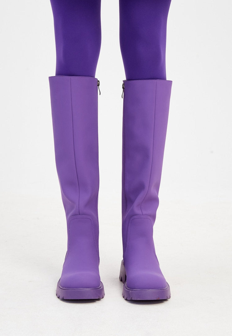 A pair of trendy knee-high chunky sole purple boots designed for women, the perfect fashion statement for any outfit.