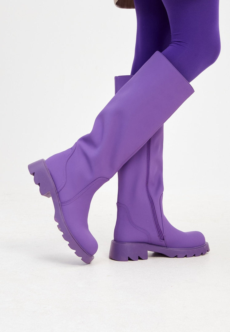 A fashionable pair of knee-high purple boots for women with chunky soles, perfect for stepping out in style.