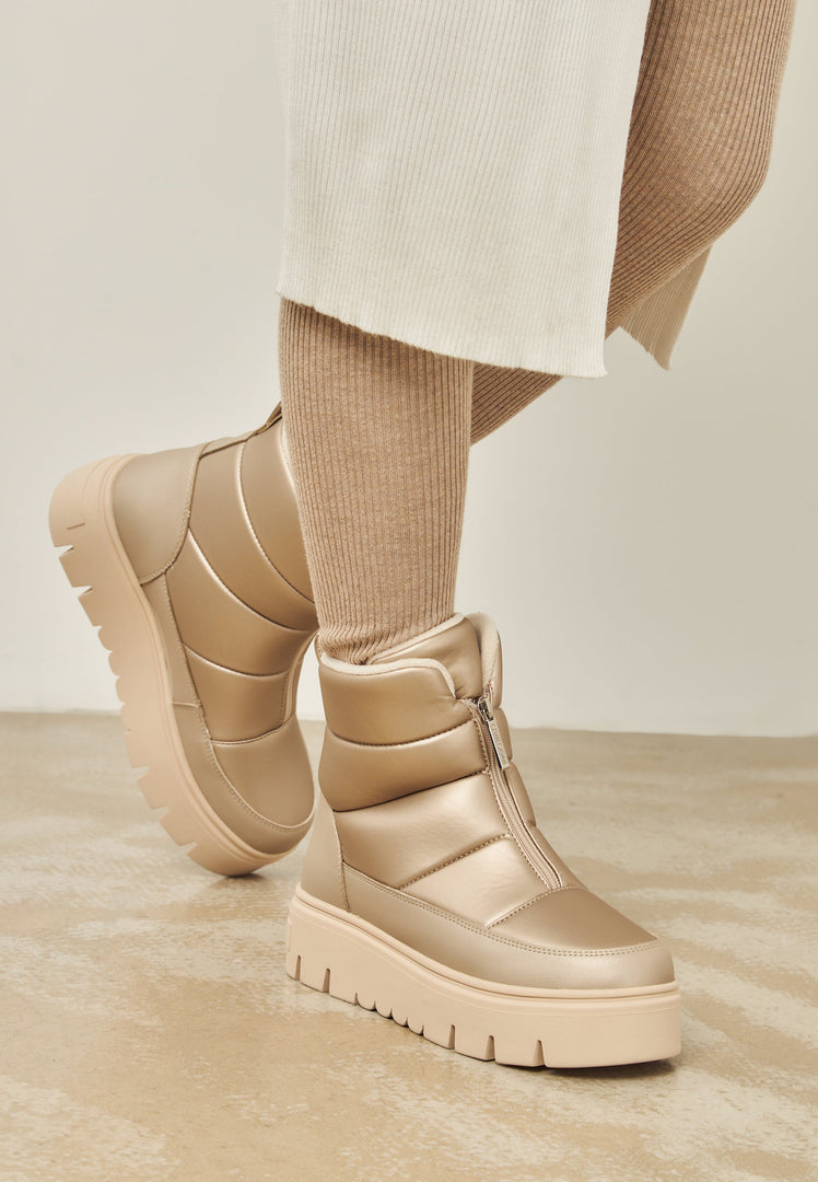 A pair of beige winter boots, ideal for snowy days, crafted in an elegant and stylish design for the cold weather season.