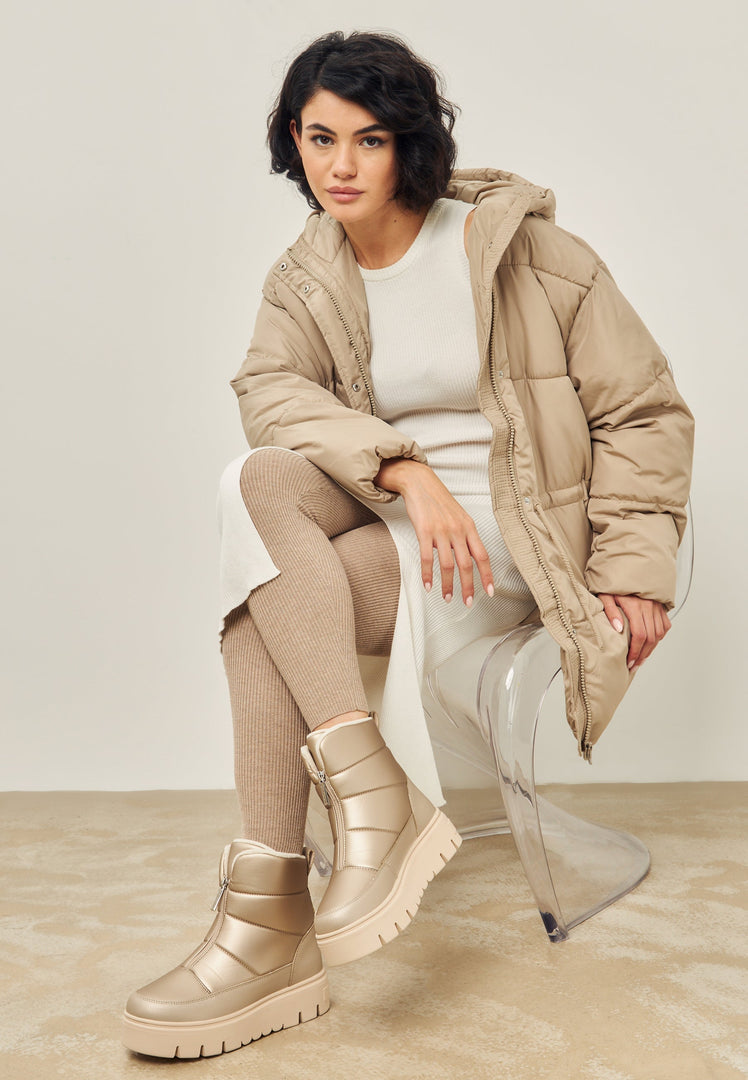 A pair of stylish beige winter boots, perfect for snowy weather and adding an elegant touch to your cold weather wardrobe.