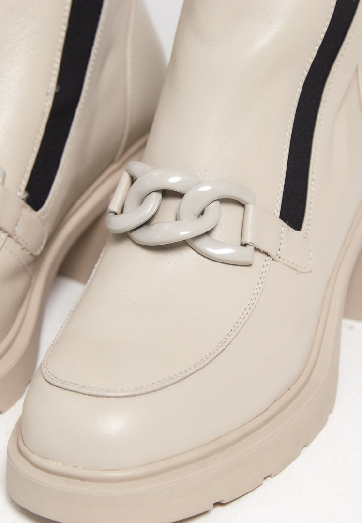A stylish pair of women's ankle boots with a chunky heel and chain detail in beige, perfect for a fashionable look.