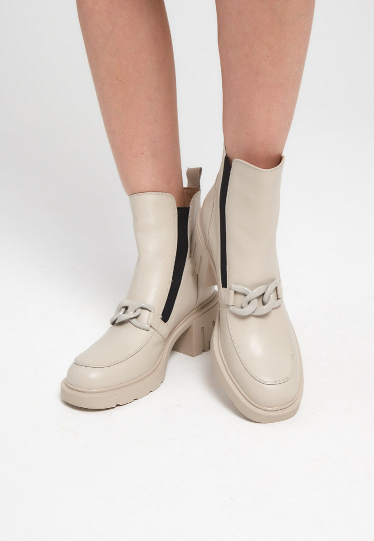 A stylish pair of chunky heel ankle boots with chain detail in beige, perfect for women looking for fashionable and trendy footwear.