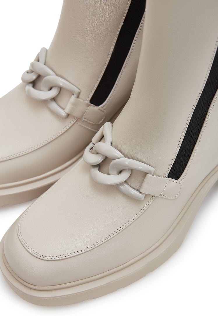 A trendy pair of women's beige ankle boots with chunky heel and stylish chain detail, perfect for a fashionable look.